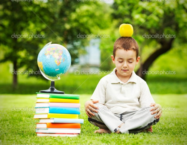 Little boy in zen meditation preparing to be good student with apple on the head